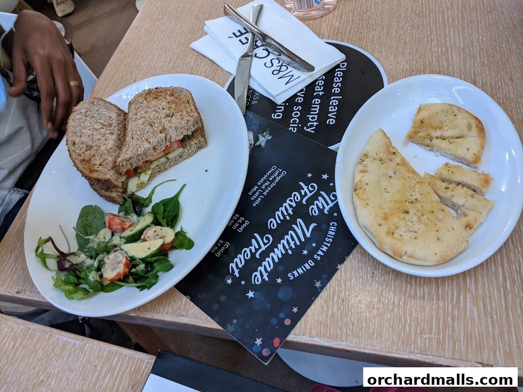 A table with a sandwich, salad, flatbread, and a festive menu from MS Café.