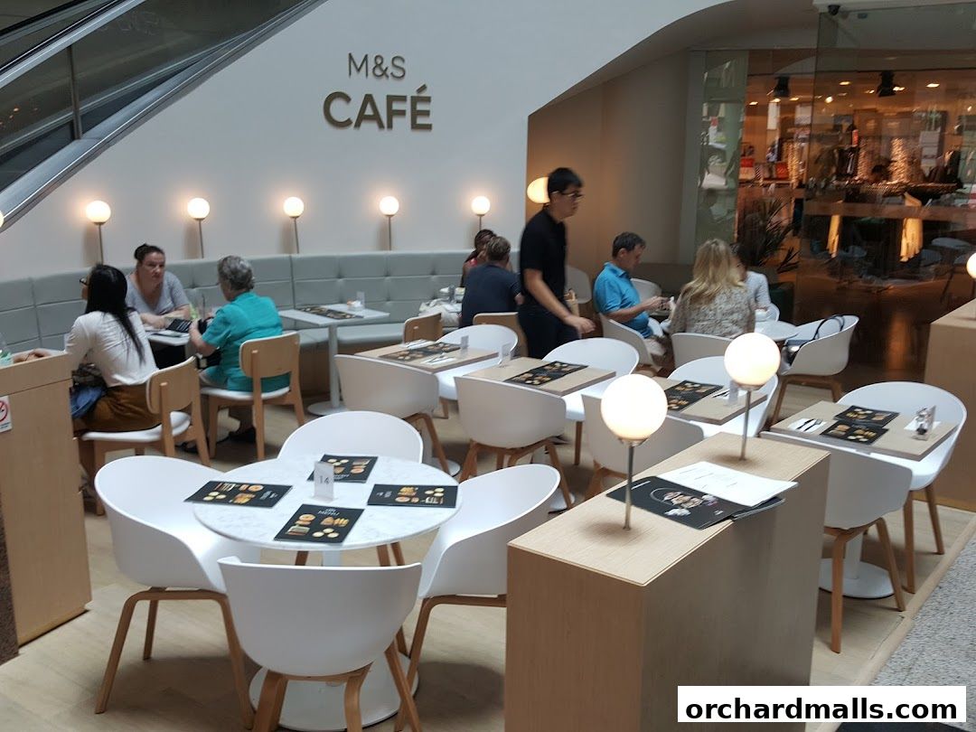 Interior of M&S Café with customers seated at tables and a modern, clean design.