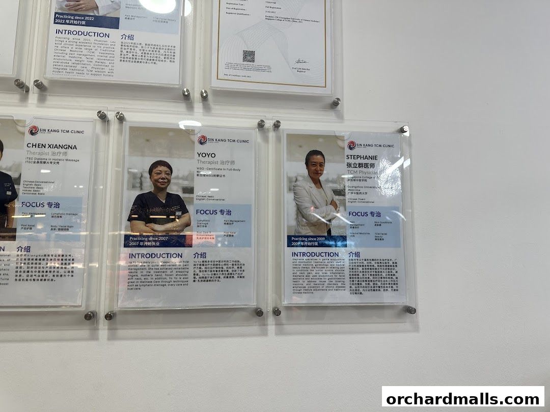 Certificates and profiles of TCM therapists displayed on a wall.