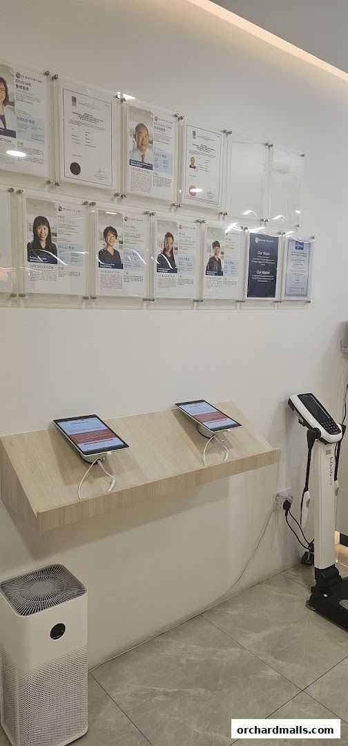 Interior of a TCM clinic with framed certificates, tablets, and a body composition analyzer.