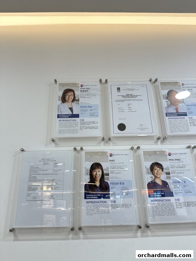 Certificates and profiles of TCM physicians displayed on a wall.