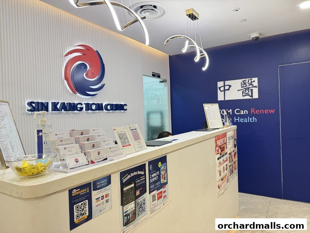 Reception area of a TCM clinic with branding, payment options, and promotional materials.