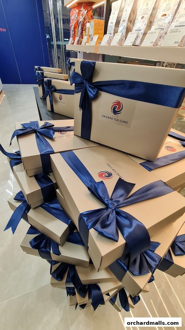 Gift boxes with blue ribbons from Sin Kang TCM Clinic displayed in a shop.