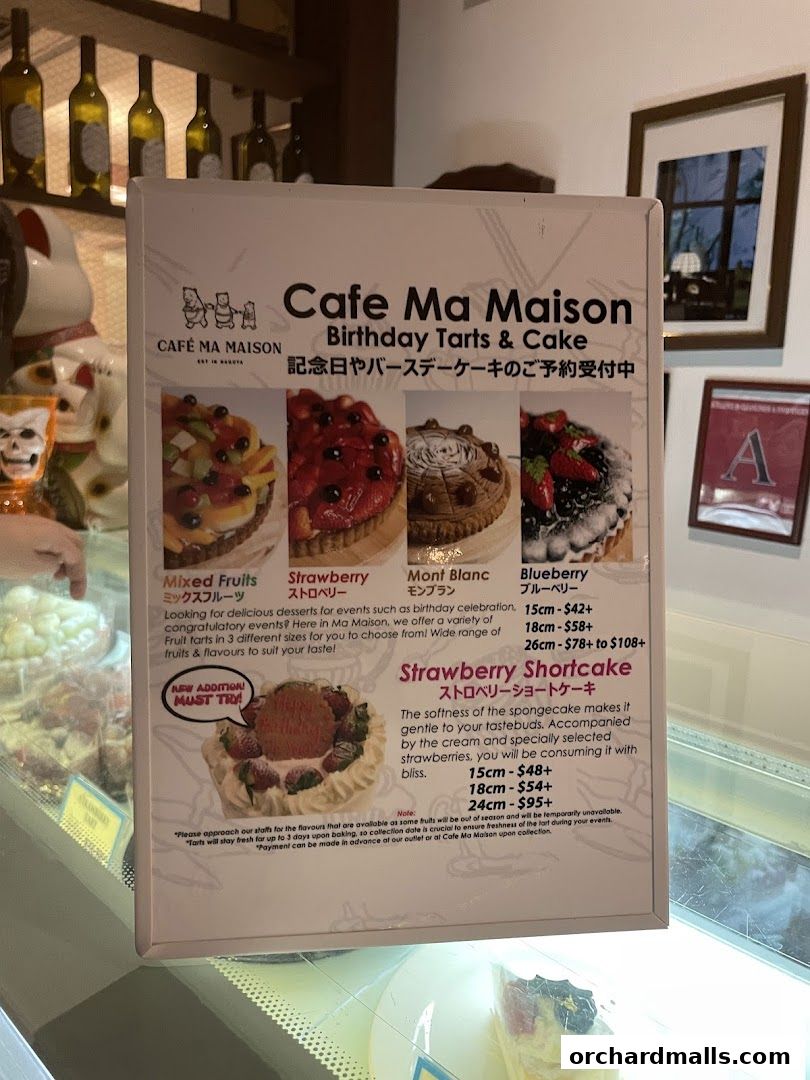 A menu board for Cafe Ma Maison showcasing birthday tarts and cakes with prices.