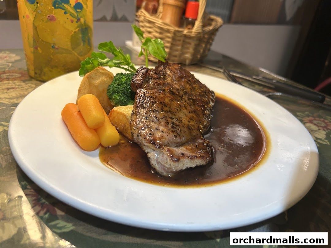A perfectly cooked steak with roasted vegetables and gravy on a white plate.