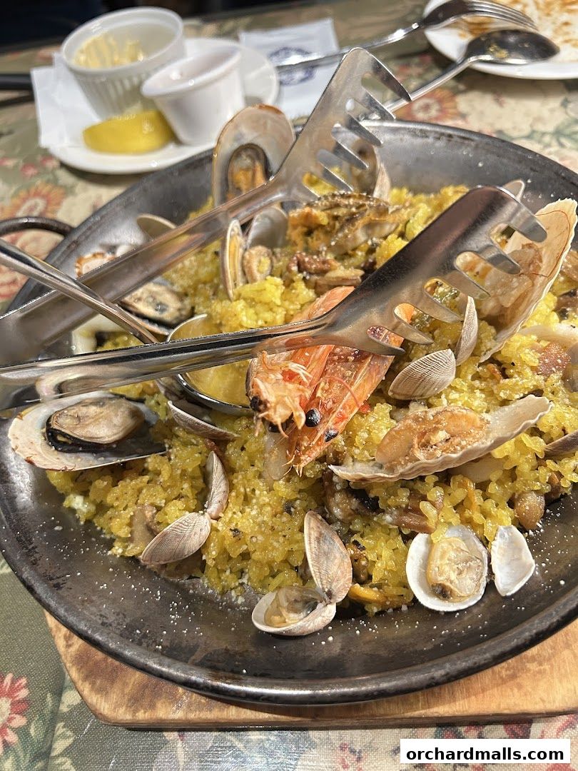 A close-up of a seafood paella dish with mussels, shrimp, and clams.