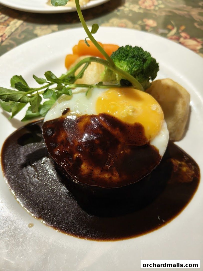 A delicious dish with a fried egg, gravy, vegetables, and a sprig of greens.