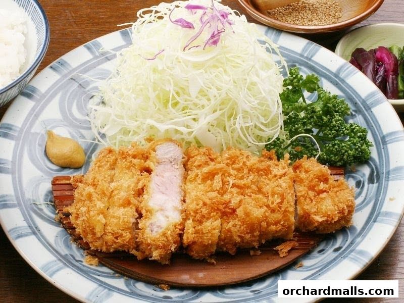 A delicious plate of tonkatsu with shredded cabbage, rice, and pickles.