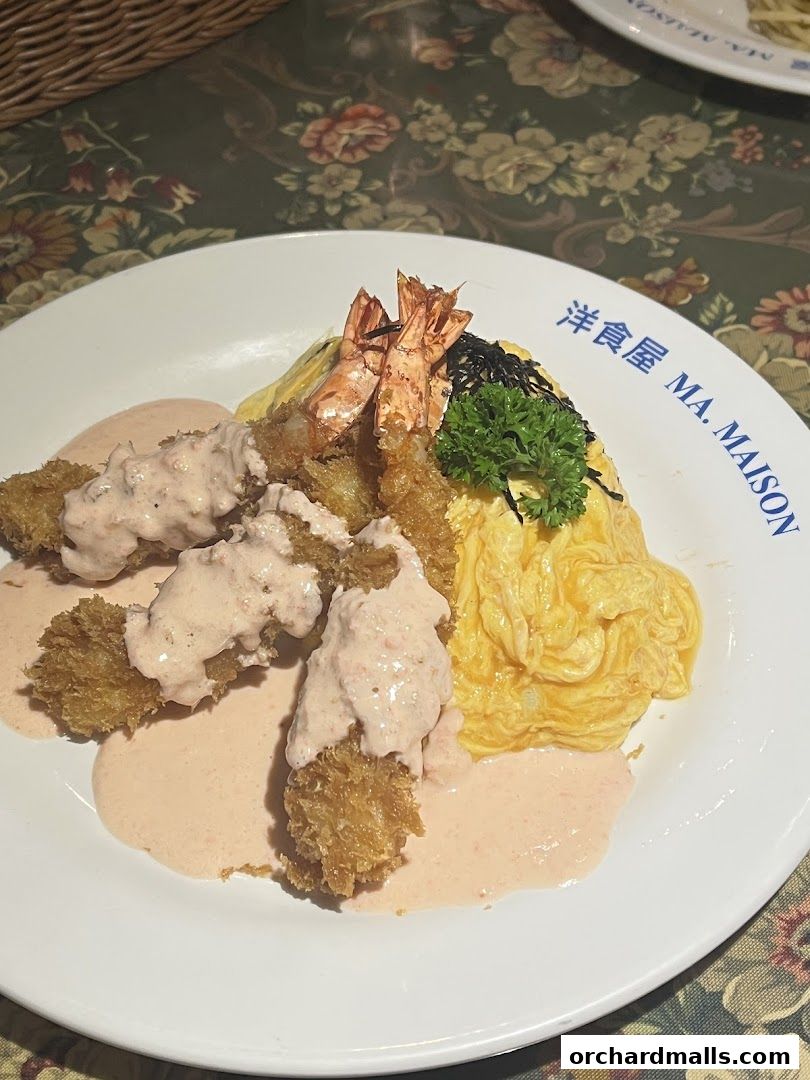A plate of omurice with fried shrimp and a creamy sauce, garnished with seaweed and parsley.