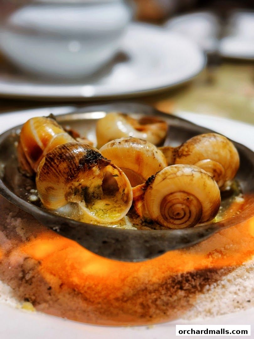 A close-up shot of escargots served in a dish with a flame underneath.