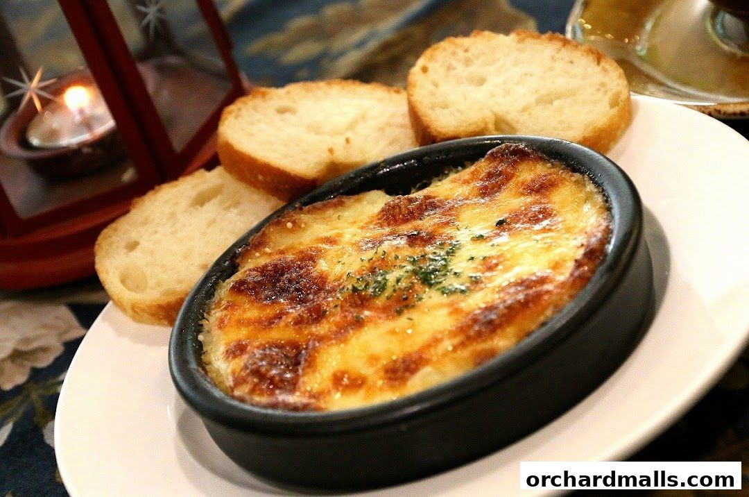 A close-up of a baked dish with melted cheese, served with bread slices and a candle.