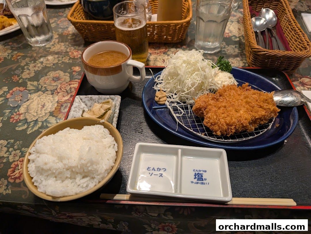 A delicious meal featuring crispy fried pork cutlet, rice, soup, and pickles.