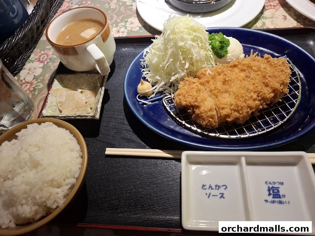 A delicious meal featuring crispy fried pork cutlet, rice, soup, and pickles.