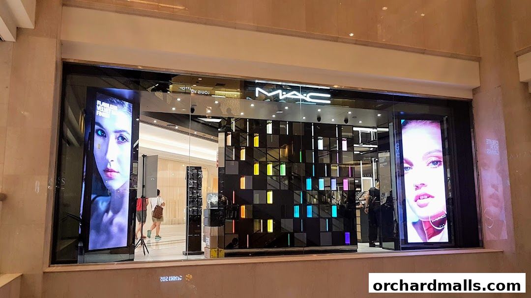 The exterior of a MAC Cosmetics store with digital displays of models and colorful product shelves.
