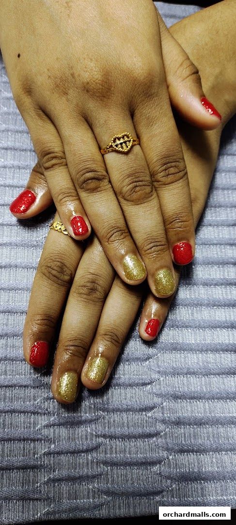 Close-up of hands with red and gold glitter nail polish and rings.