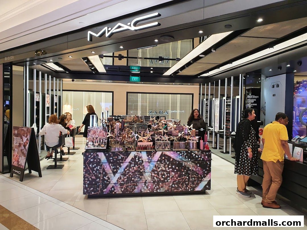 MAC Cosmetics store entrance with makeup displays and customers.