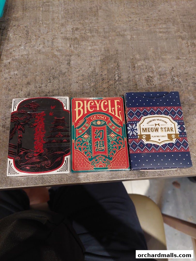 Three decks of playing cards with intricate designs are displayed on a textured surface.