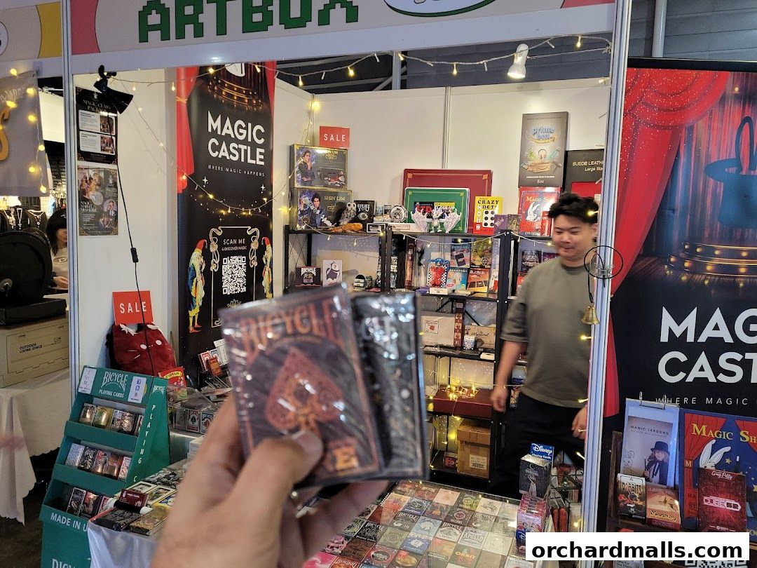 A person holds a deck of playing cards in front of a magic shop display.