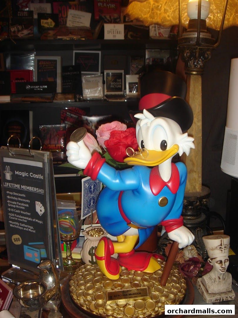 A display featuring a Scrooge McDuck statue surrounded by magic-themed items and merchandise.