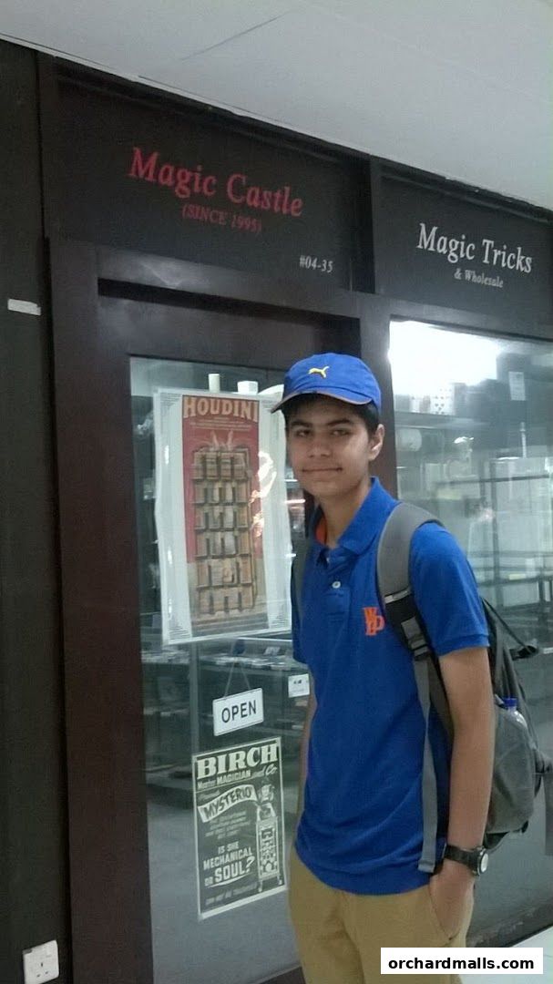 A young person stands in front of the Magic Castle shop, which sells magic tricks and wholesale.