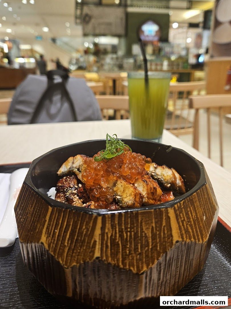 A bowl of unagi don with ikura and a green drink on a tray.