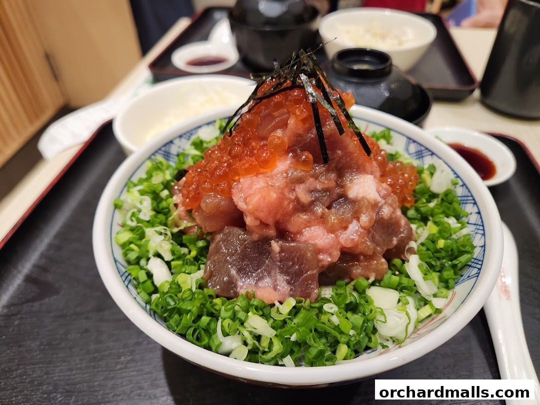 A close-up of a delicious bowl of tuna and salmon roe donburi with chopped green onions.