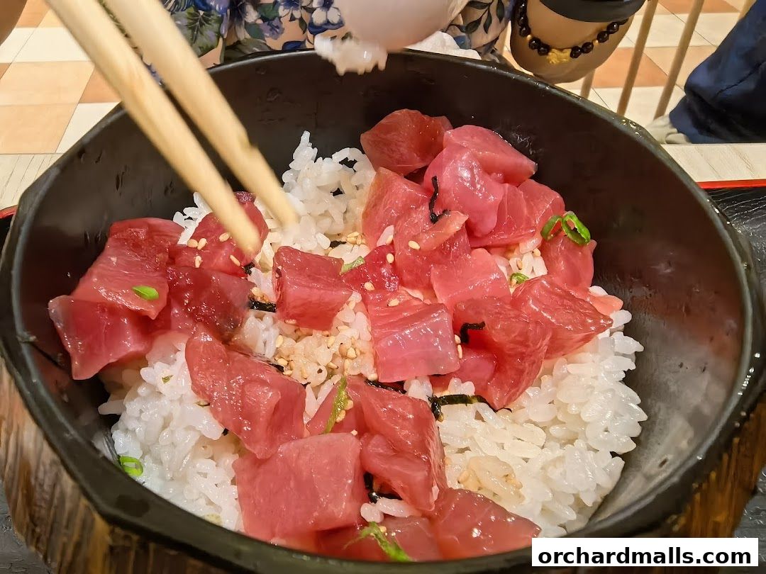 A close-up of a delicious tuna donburi being served with chopsticks.