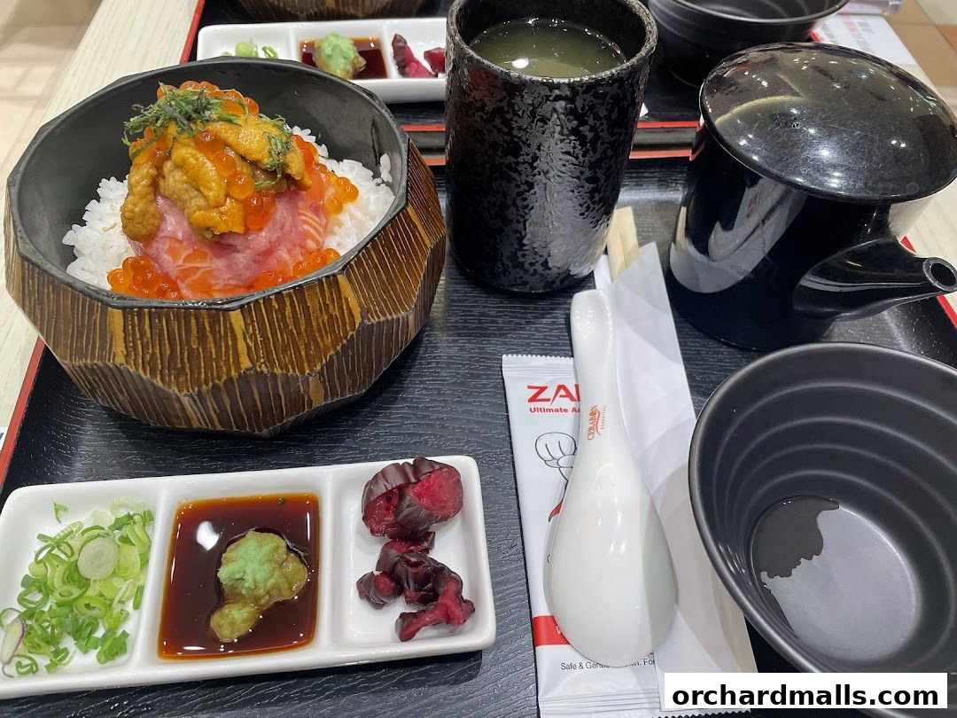 A delicious bowl of rice topped with salmon, uni, and ikura, served with side dishes.
