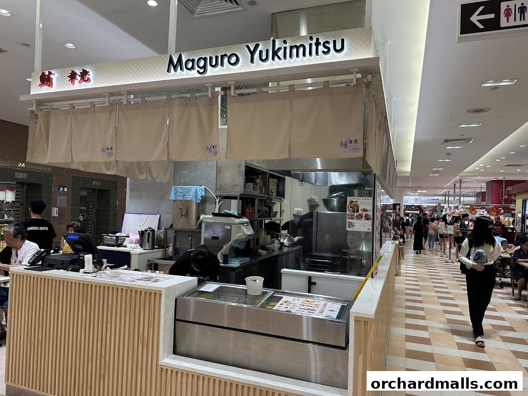 A Japanese restaurant counter with staff preparing food and a menu displayed.