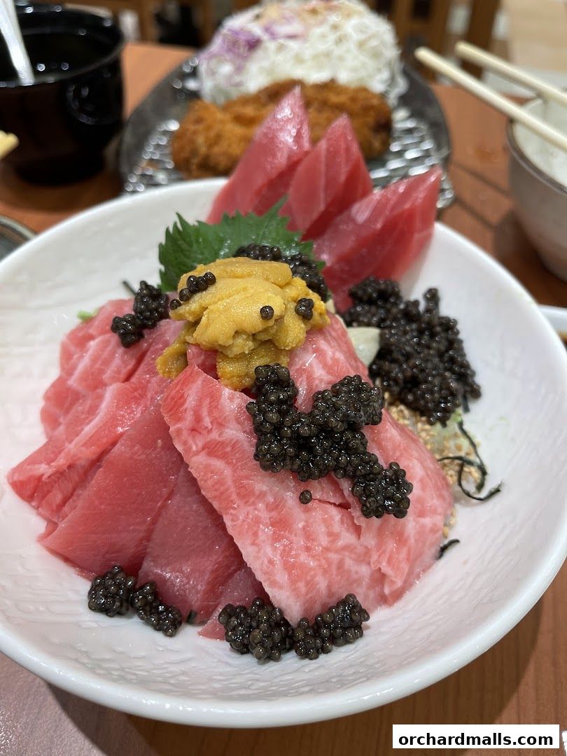 A close-up of a tuna sashimi dish topped with uni and caviar.