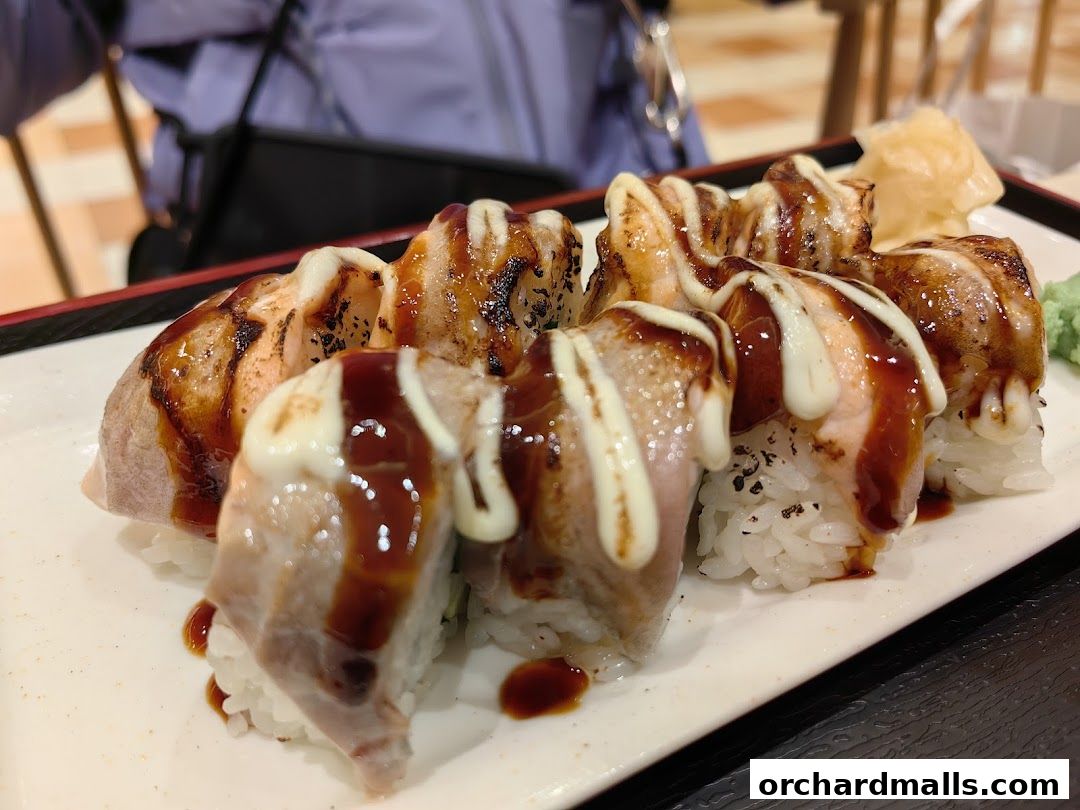 A plate of delicious sushi rolls topped with sauce and mayonnaise.