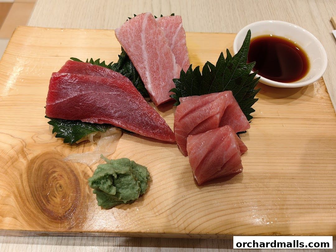 A wooden platter with fresh tuna sashimi, wasabi, and soy sauce.