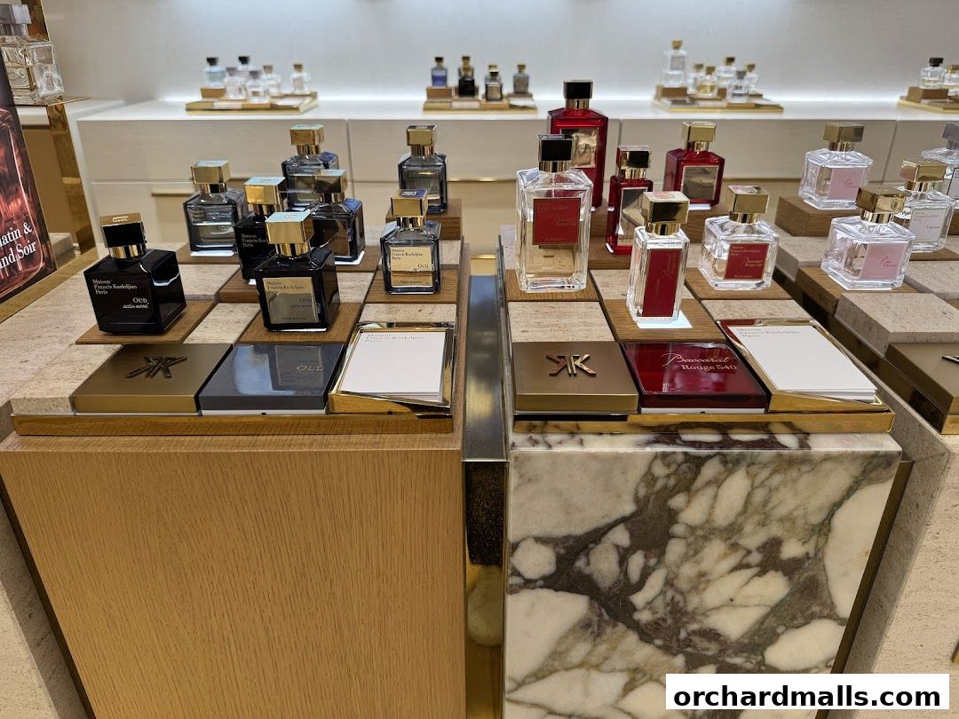 Display of Maison Francis Kurkdjian perfumes in elegant bottles on tiered shelves.