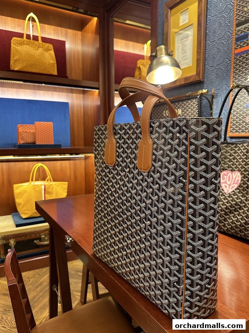 Goyard tote bags displayed on a wooden table and shelves in a luxury boutique.