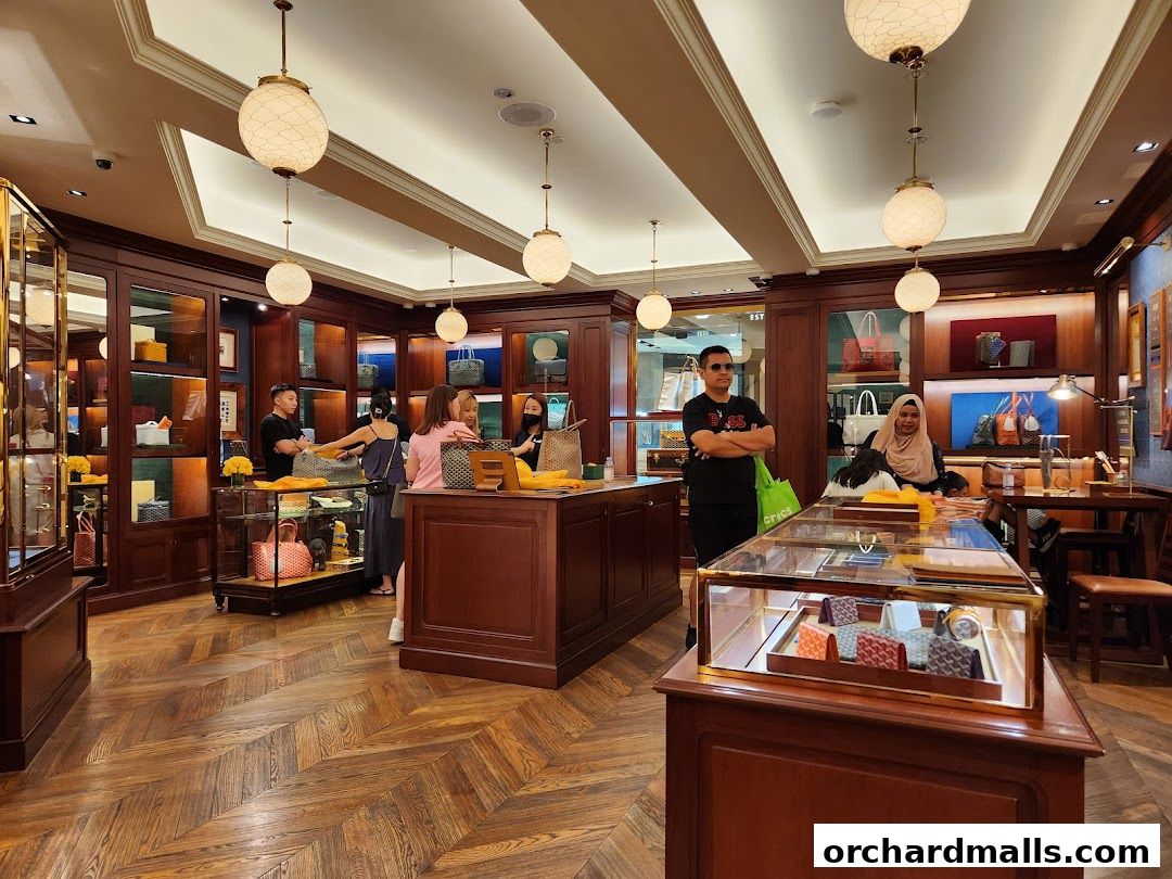 Interior of a luxury boutique with display cases and customers browsing handbags.