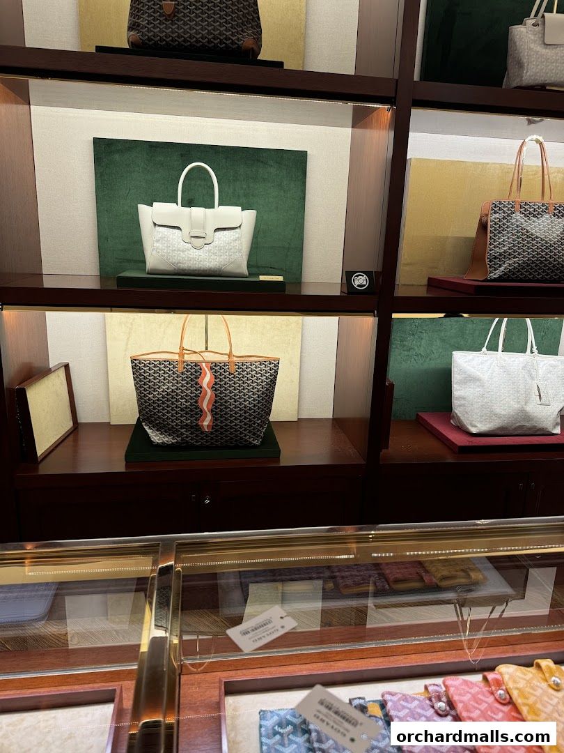 Display of luxury Goyard handbags and accessories in a well-lit retail store.