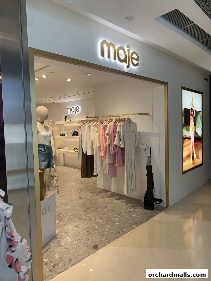 The entrance of a Maje clothing store, showcasing a mannequin and racks of stylish apparel.