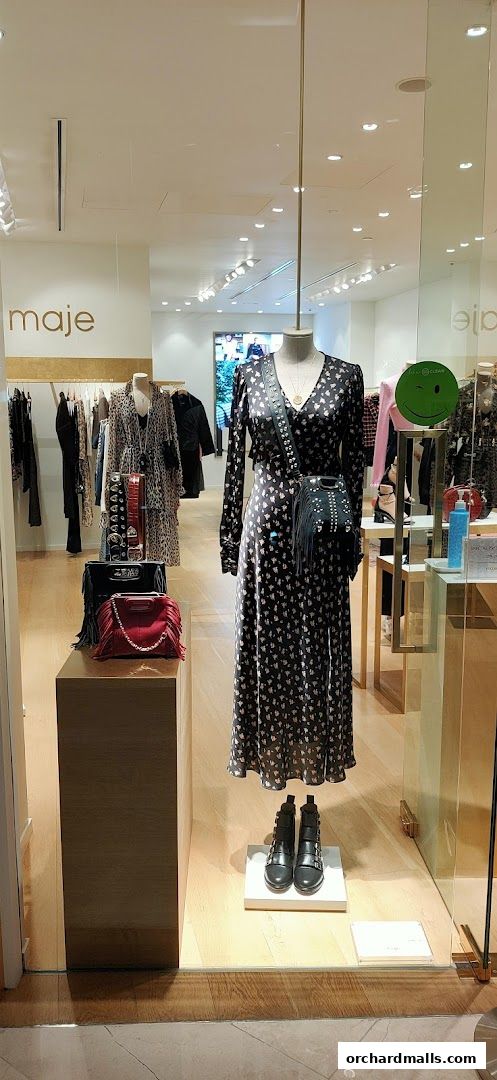 Maje shop window display featuring a patterned dress, handbags, and boots.