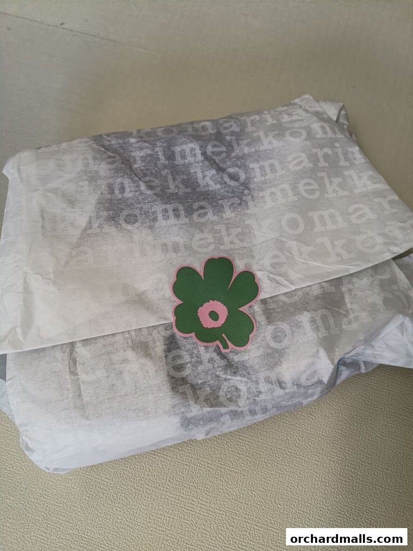 A Marimekko branded shopping bag with tissue paper and a flower logo.