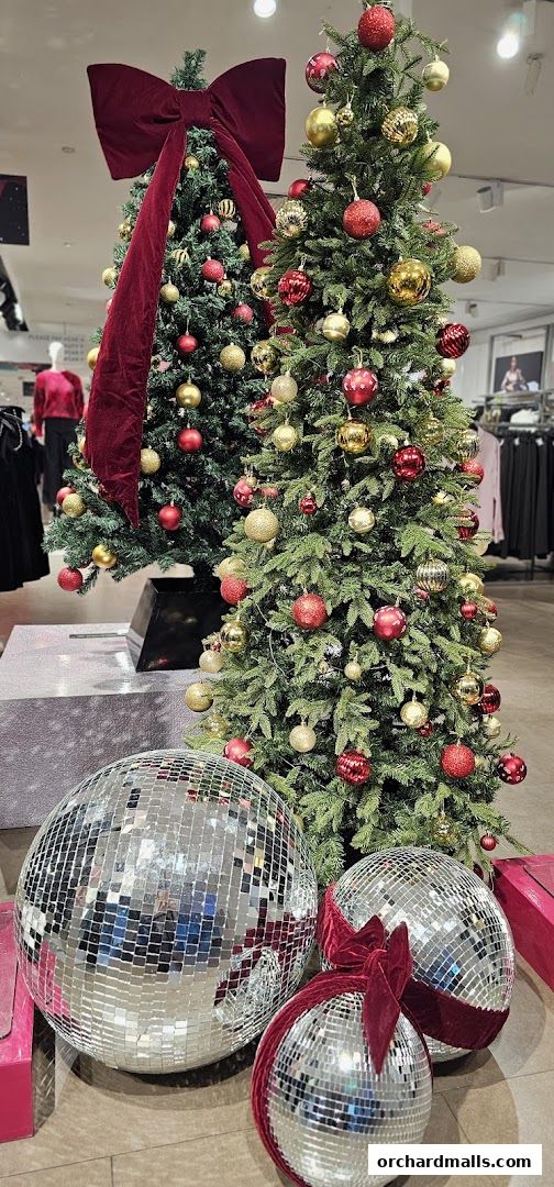 Festive Christmas trees decorated with red and gold ornaments and large disco balls.
