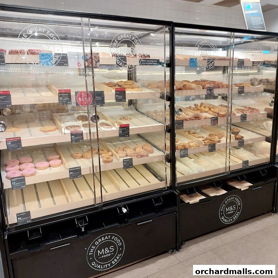A display case filled with various baked goods and pastries at Marks & Spencer.