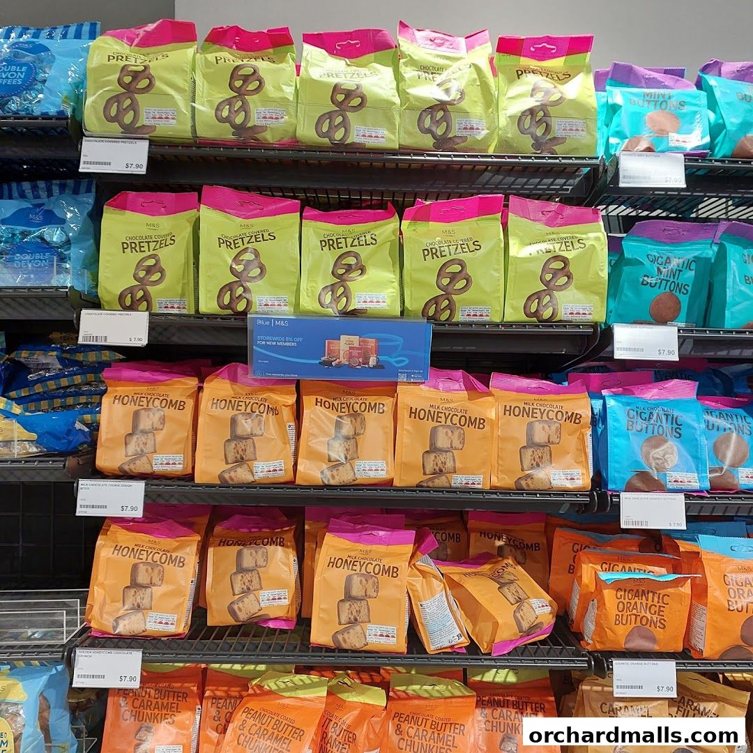 Shelves stocked with various M&S branded snacks like pretzels, honeycomb, and chocolate buttons.