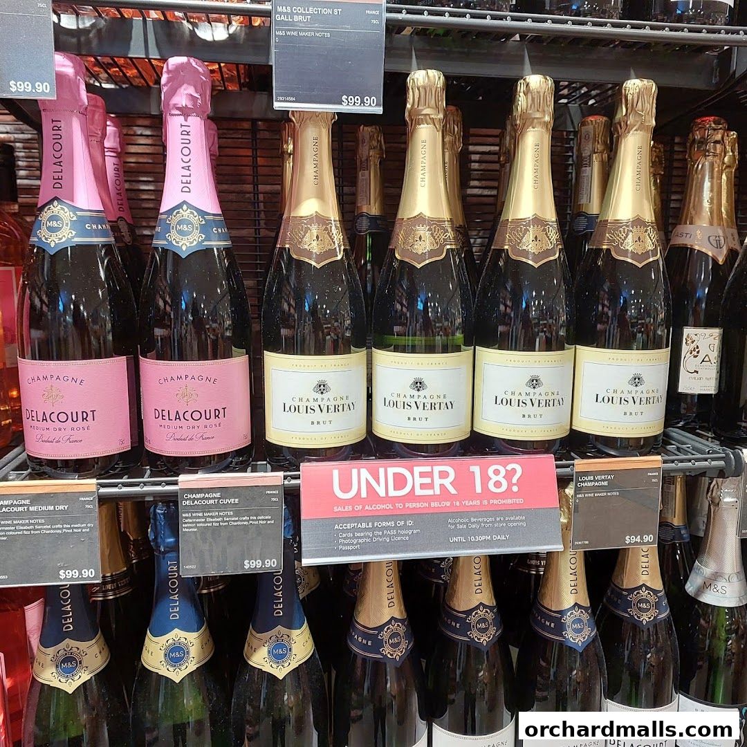 A display of various champagne bottles, including Delacourt and Louis Vertay, with price tags and an age restriction sign.