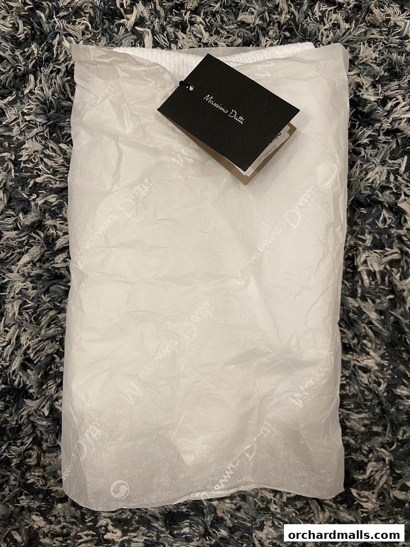 A Massimo Dutti branded shopping bag with tissue paper and a tag on a textured surface.