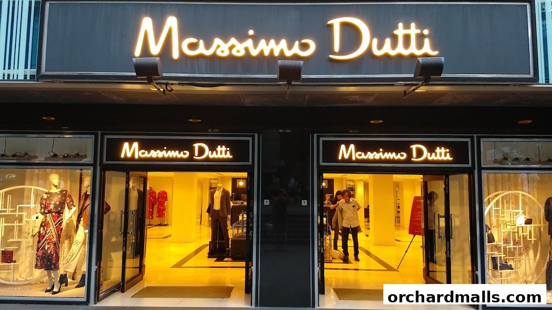 The illuminated storefront of Massimo Dutti, featuring mannequins and open doors.