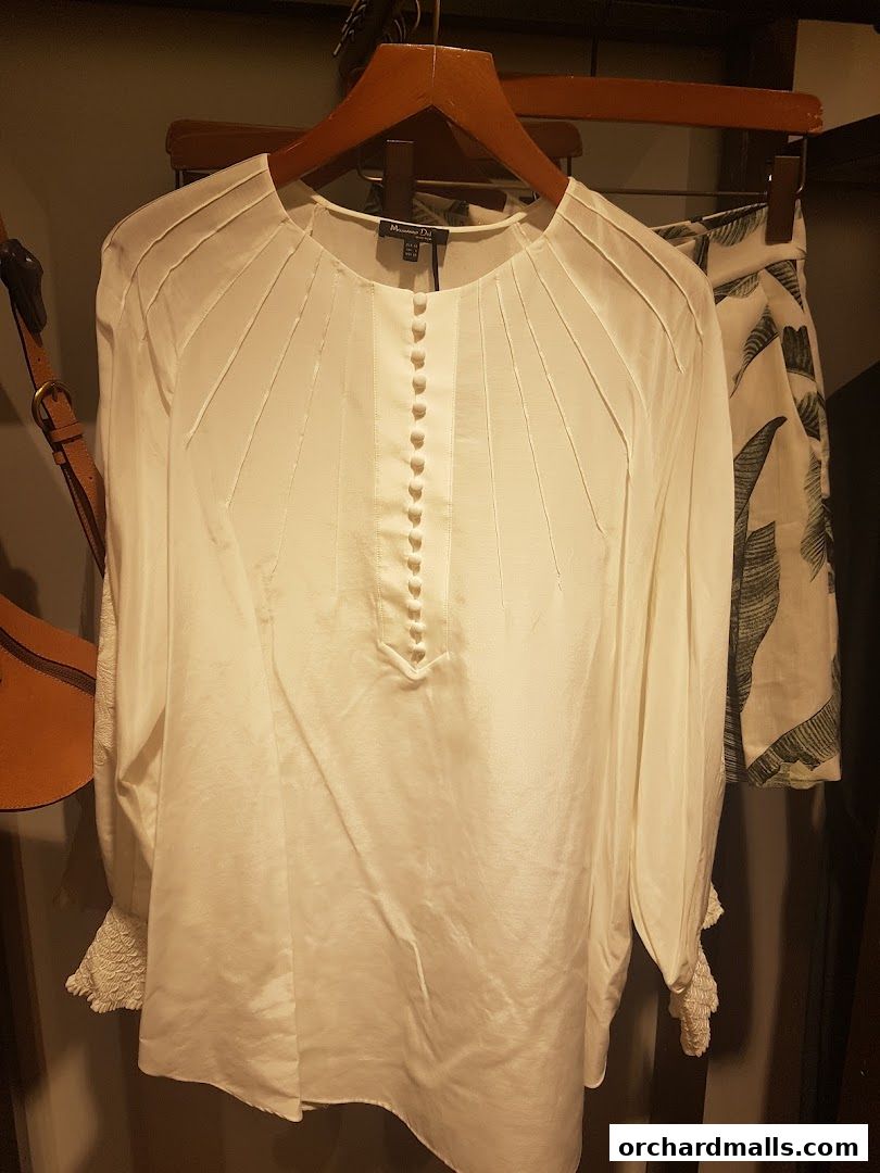 A white satin blouse with button detailing and pleated front, displayed on a hanger.