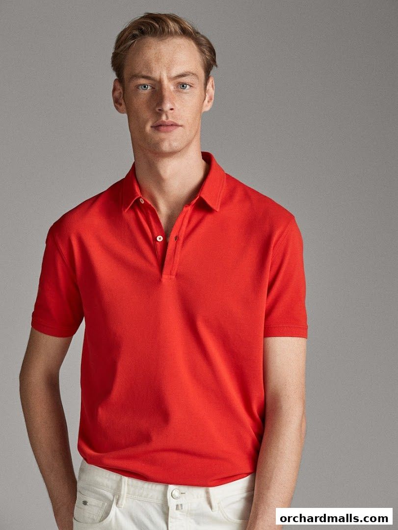 A man models a bright red polo shirt and white jeans against a neutral background.