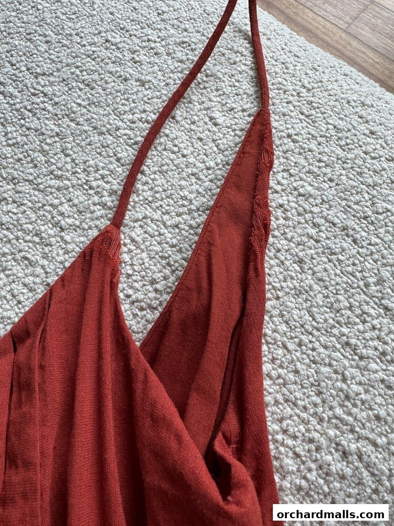 Close-up of a rust-colored dress with thin straps and a V-neckline.