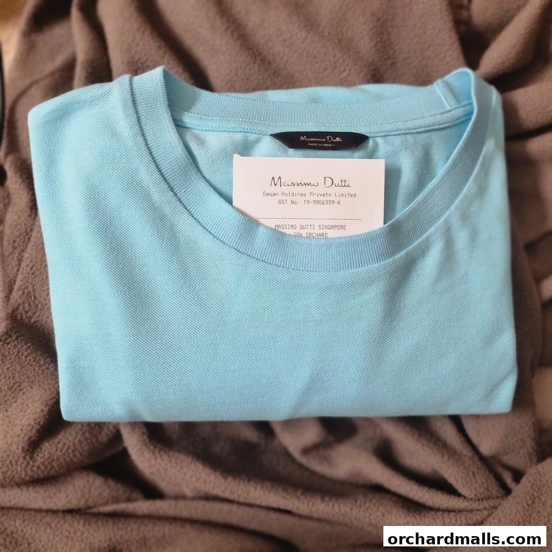 A light blue Massimo Dutti polo shirt folded with a receipt inside.