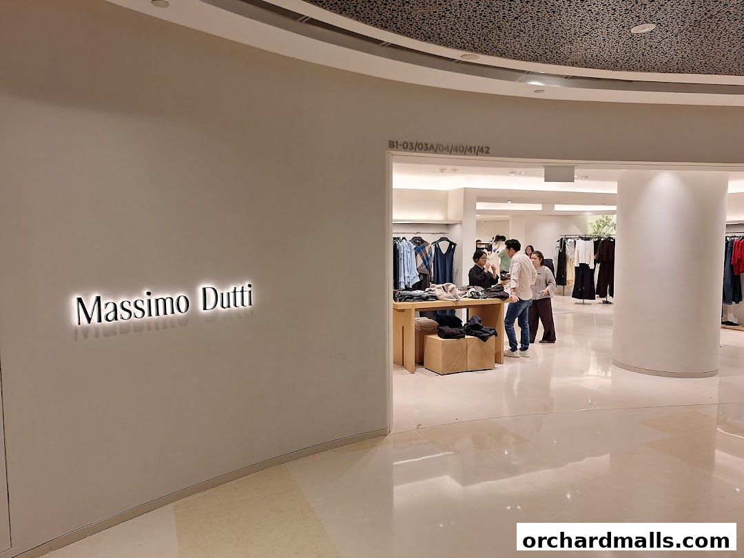 The entrance to the Massimo Dutti store, showcasing its illuminated logo and a glimpse of the clothing inside.